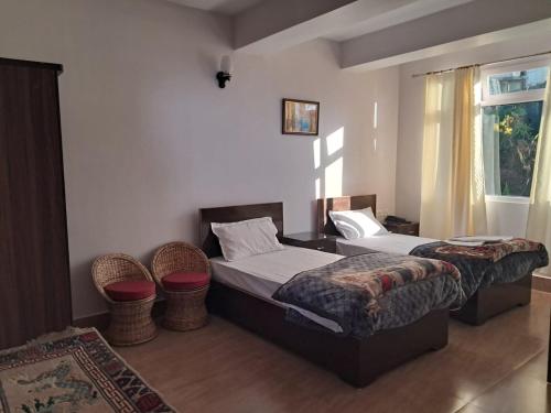 a bedroom with two beds and a window at The Sherpa's Abode in Gangtok