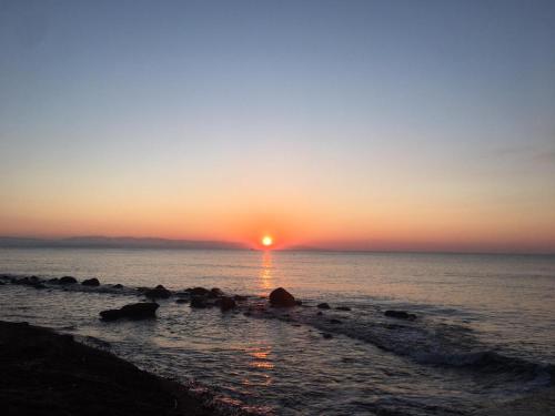 a sunset over the ocean with rocks in the water at Ajò Faci a Mari in Capoterra