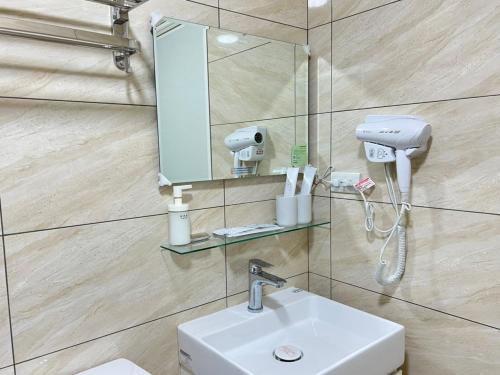 een badkamer met een wastafel en een spiegel bij Hourlight Homestay in Ch'iung-lin
