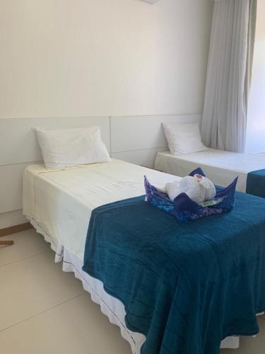 two beds with a stuffed animal on a blue blanket at Imbassaí Bahia Temporada Térreo in Imbassai