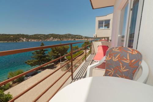 a balcony with a table and chairs overlooking the water at Rozali Tisno Apartments in Tisno