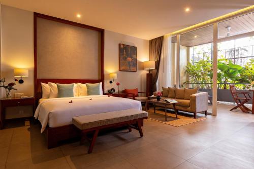 Indra Hotel في بنوم بنه: غرفة نوم بسرير واريكة وكرسي
