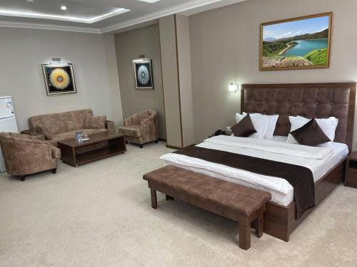 ブハラにあるGrand Shirin Palace Buxのベッドルーム(大型ベッド1台付)、リビングルームが備わります。