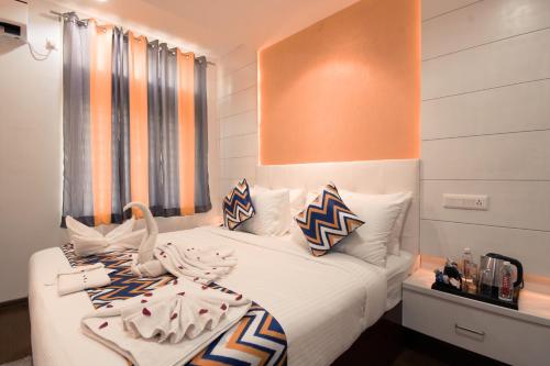 a bedroom with a bed with white sheets and pillows at Athulya Residence Suite Rooms in Bengaluru