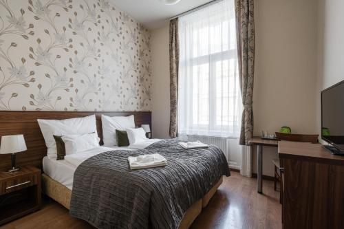 a bedroom with a bed and a desk and a television at Elit Boutique Rooms- Best Location by BQA in Budapest