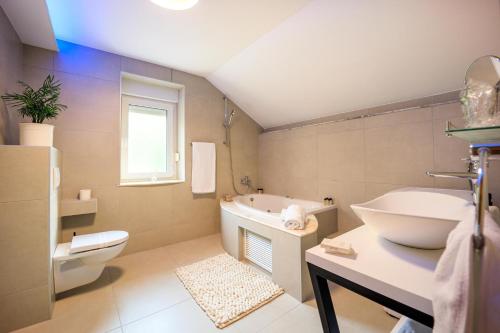 ein Badezimmer mit einer Badewanne, einem WC und einem Waschbecken in der Unterkunft Villa Aljmaš in Aljmaš