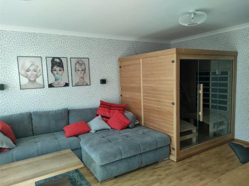 Appartement Bella Vista في كراجسكا غورا: غرفة معيشة مع أريكة زرقاء مع وسائد حمراء