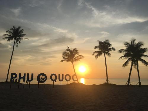 un cartel en una playa con palmeras y puesta de sol en Minh Anh Hotel, en Phu Quoc