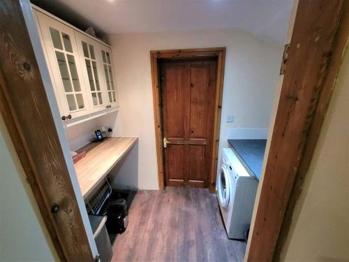 a small kitchen with a wooden door and a washing machine at Nice 4-bedroom vacation home with indoor fireplace in Wellington