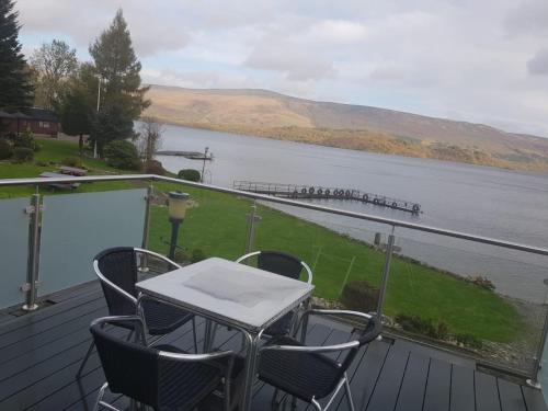 a table and chairs on a deck overlooking a body of water at Culag Lochside Self Catering in Luss