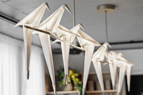 a group of white paper airplanes hanging from a ceiling at Stay KooooK Bern Wankdorf - Online Check In in Bern