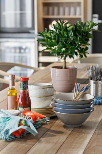 a wooden table with bowls and plates and a potted plant at Stay KooooK Bern Wankdorf - Online Check In in Bern