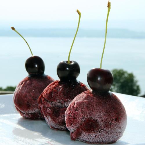 three pomegranates with black cherries on top on a table at Guggital Hotel Restaurant in Zug