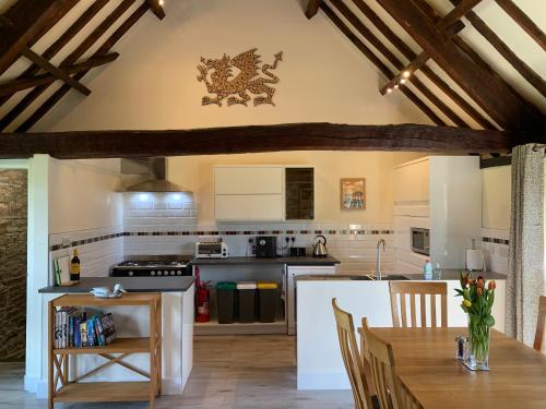a kitchen with wooden ceilings and a table with chairs at The Longhouse, Brecon Beacons (King & Twin) in Brecon