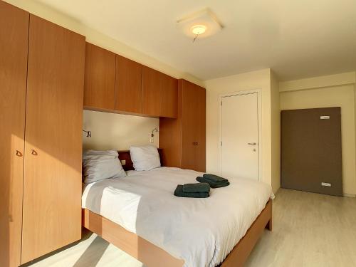 a bedroom with a large bed with wooden cabinets at Residentie Laurence - 'SEAGIRL' in Oostduinkerke