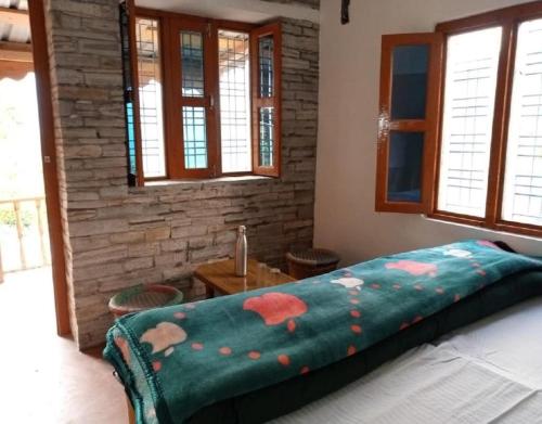 a bedroom with a bed with a green blanket at Himalayan Hills Village Retreat by StayApart, Ukhimath in Rudraprayāg