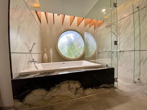 uma casa de banho com uma banheira e uma janela redonda em Movenpick Pool villa by Angkana em Na Jomtien