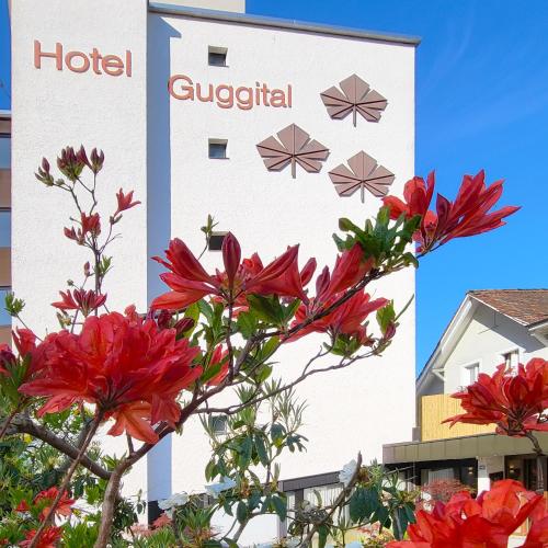 a hotel with red flowers in front of a building at Guggital Hotel Restaurant in Zug