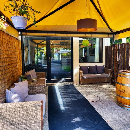 a patio with a large yellow tent with couches and a barrel at Guggital Hotel Restaurant in Zug