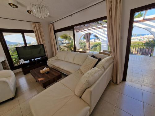 a living room with a white couch and a television at The Belvedere Villa Latchi in Lachi