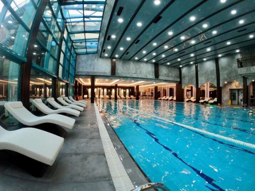 a large swimming pool with white chairs in a building at Ramada by Wyndham Sofia City Center in Sofia