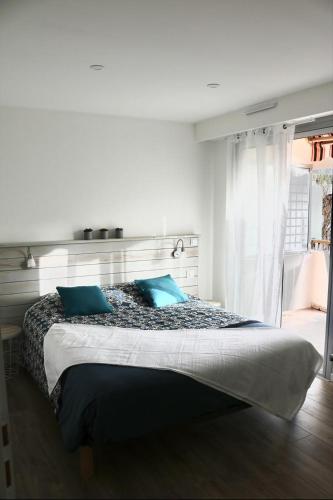 une chambre avec un lit avec deux oreillers bleus dans l'établissement Bel appartement terrasse au 4ème et dernier étage, à Mandelieu-la-Napoule