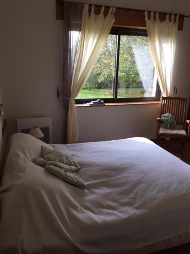 1 cama blanca en un dormitorio con ventana en Le clos saint Jean, en Dragey