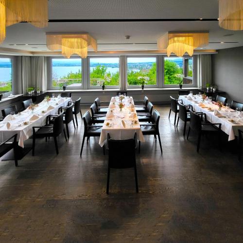 a dining room with white tables and chairs and windows at Guggital Hotel Restaurant in Zug