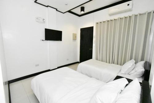 two beds in a room with white walls at Swiftlets Inn in El Nido