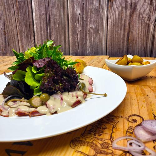 a white plate with a salad on a wooden table at Guggital Hotel Restaurant in Zug