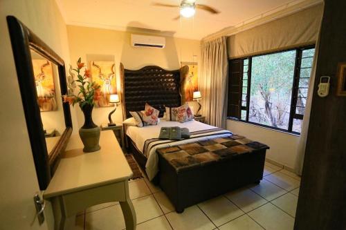 Schlafzimmer mit einem Bett, einem Tisch und einem Fenster in der Unterkunft Ukweza Guest House in Marloth Park