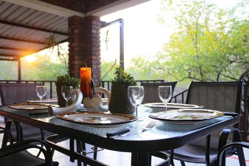 einen Tisch mit Tellern und Weingläsern auf einer Terrasse in der Unterkunft Ukweza Guest House in Marloth Park
