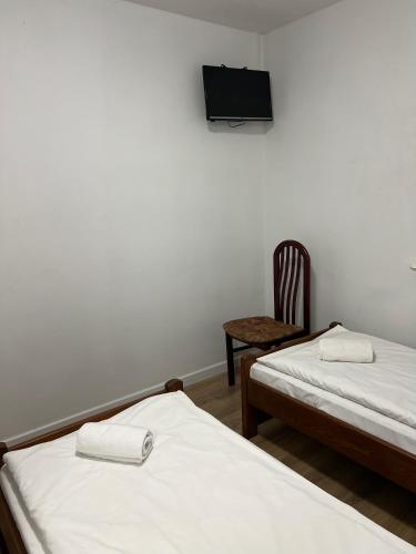 two beds in a room with a tv on the wall at Motel S7 in Goszczyn