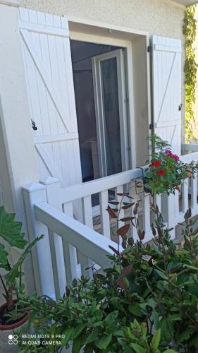 a white porch with a door and some flowers at Chambre d hôte à 20 min de VERSAILLES in Le Mesnil-Saint-Denis