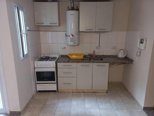 una pequeña cocina con armarios blancos y fregadero en Hermoso monoambiente en complejo residencial. en Godoy Cruz