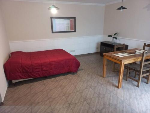 1 dormitorio con cama roja y mesa en Hermoso monoambiente en complejo residencial. en Godoy Cruz