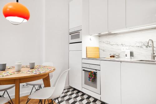 una cocina con armarios blancos y una mesa con sillas. en HOUSEHOST Apartment :Starowiślna 66/9 Street en Cracovia