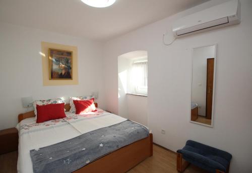 sypialnia z łóżkiem z czerwonymi poduszkami i oknem w obiekcie Apartment Milijana w mieście Punat