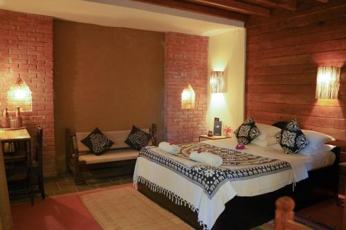 a bedroom with a bed and a couch in a room at Sapana Village Lodge in Sauraha