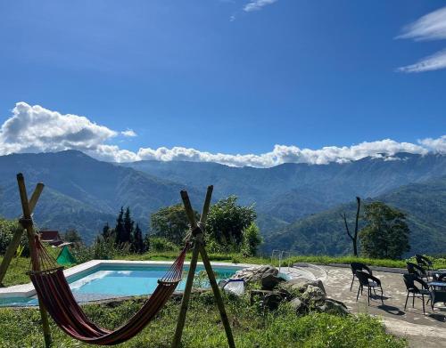 a pool with two hammocks and a view of mountains at Dharti - The Glamping Haven by StayApart in Bijanbāri Bāzār