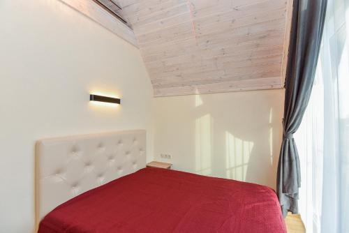 a bedroom with a red bed and a window at Kopų ramybė in Palanga