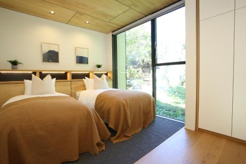 two beds in a room with a large window at Hérisson - A Valley Chalets Signature Residence in Hakuba