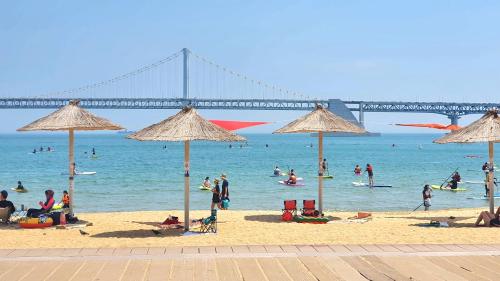 un grupo de personas en una playa con un puente en JJ House Gwangan Beach en Busan