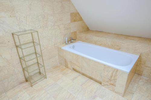 La salle de bains est pourvue d'une baignoire blanche et d'une étagère. dans l'établissement 1898 Suite, à Varsovie