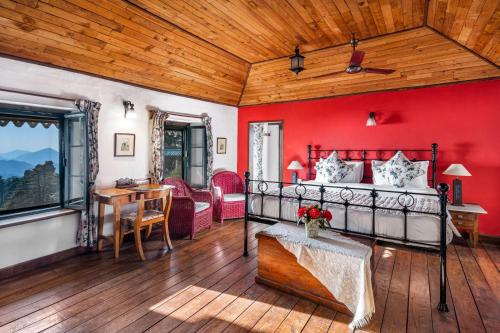 a bedroom with red walls and a bed and a table at Rokeby Manor in Mussoorie