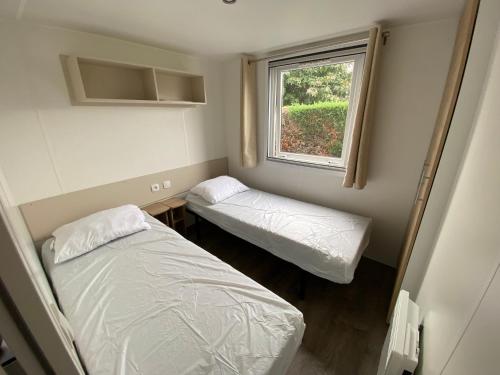 une petite chambre avec deux lits et une fenêtre dans l'établissement Camping Les Charmettes-Mobile Home Vacances, aux Mathes