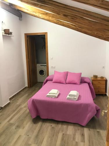 een slaapkamer met een paars bed met 2 handdoeken erop bij Vivienda el Olivar in Mogón