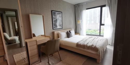 een slaapkamer met een bed, een bureau en een raam bij Asok - Din Daeng Apartment in Bangkok