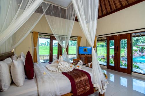 Schlafzimmer mit einem großen Bett und weißen Vorhängen in der Unterkunft Intan Villa & Suite Ubud in Ubud