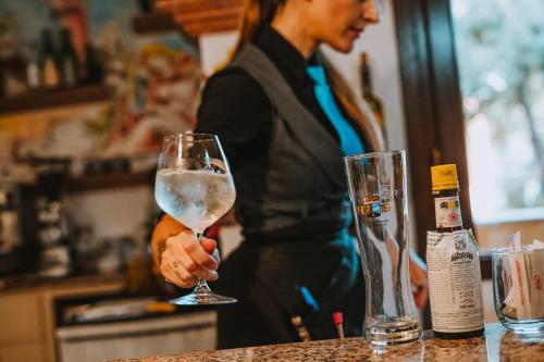 a woman standing at a counter holding a wine glass at I Ginepri Hotel in Cala Gonone